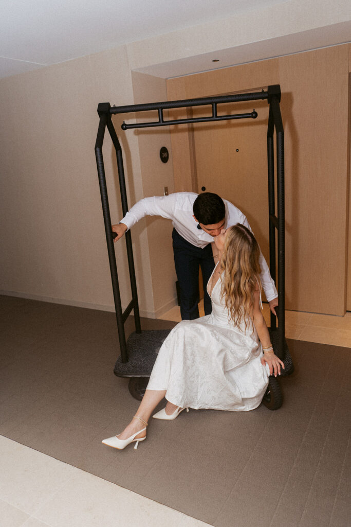 Married couple kissing on a luggage cart at The Satire hotel in Virginia