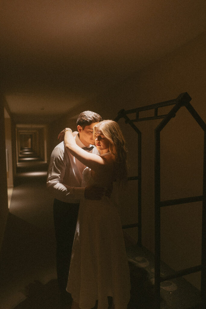 Married couple hugging in hallway wearing their wedding attire in Virginia hotel