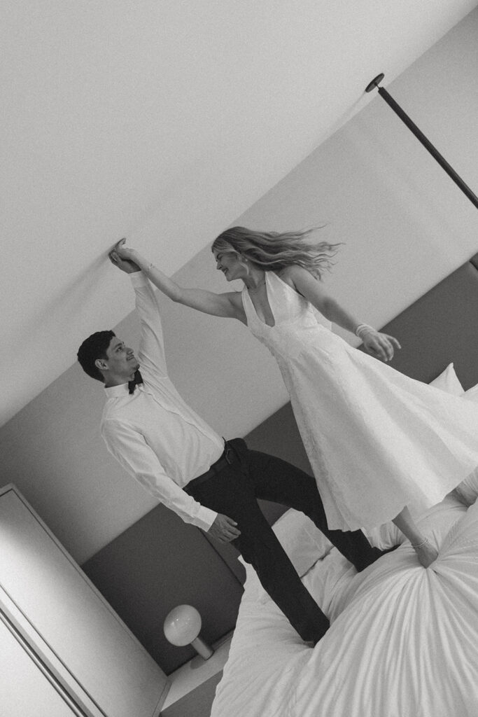 Couple having fun dancing on the bed at their hotel after eloping in Virginia